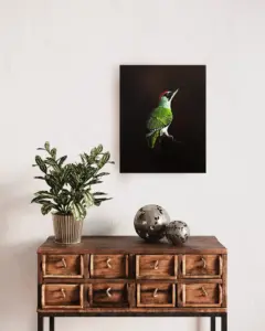 Das Foto zeigt das Gemälde eines Grünspechts, eingefügt in ein Interieur mit einer Holzkommode.