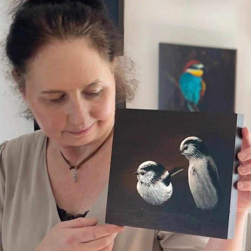 Künstlerin Simone Hofmann im Atelier mit einem originalen Chiaroscuro-Gemälde zweier Schwanzmeisen